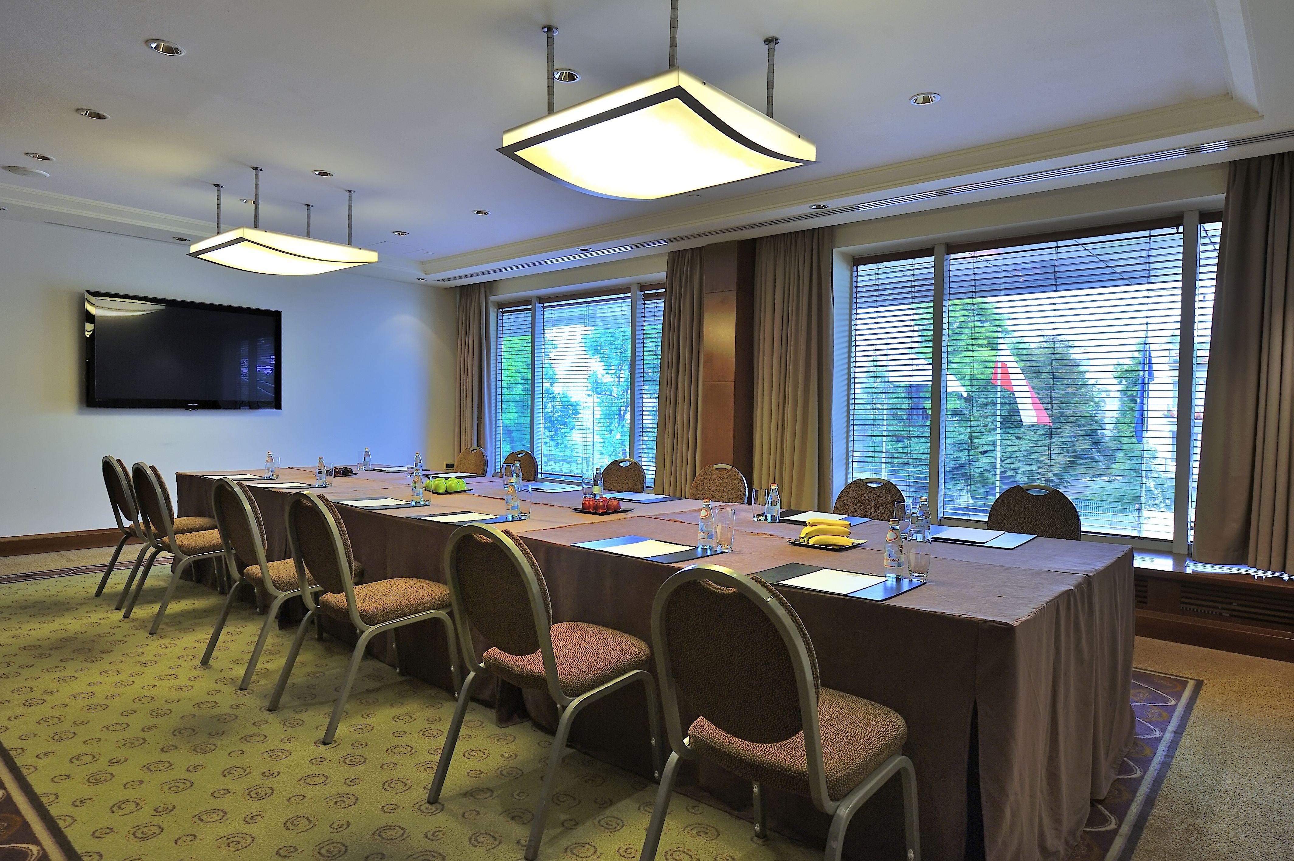 Regent Warsaw Hotel Buitenkant foto The photo shows a conference room set up for a meeting. There is a long table covered with a brown tablecloth, surrounded by several chairs. On the table, there are items likely for the meeting, such as notepads, pens, and some fruit or snacks. The r