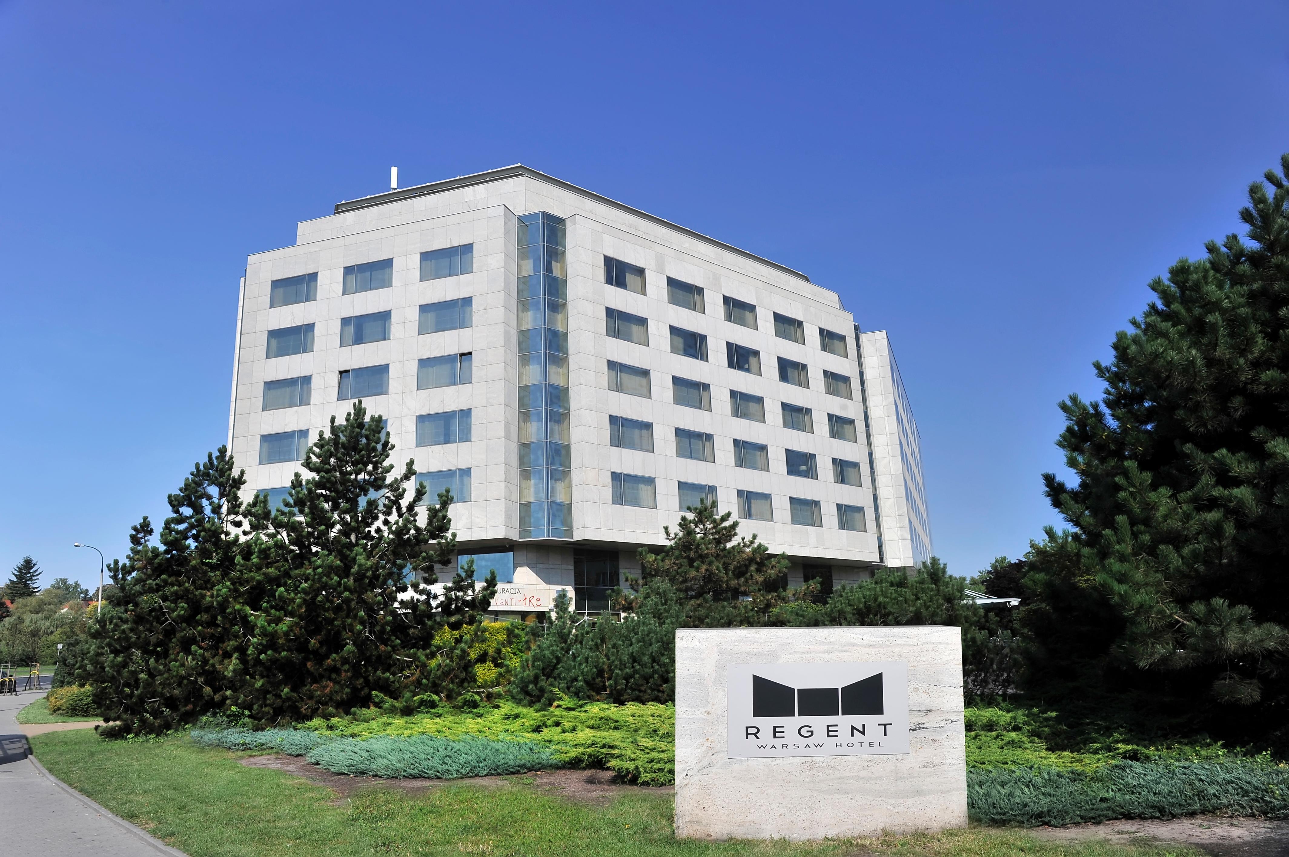 Regent Warsaw Hotel Interieur foto The photo shows a modern building with a distinct architectural design, featuring a flat roof and large windows. It appears to be a multi-story structure, likely a hotel or office building, with a clean and contemporary facade. In front of the buildi