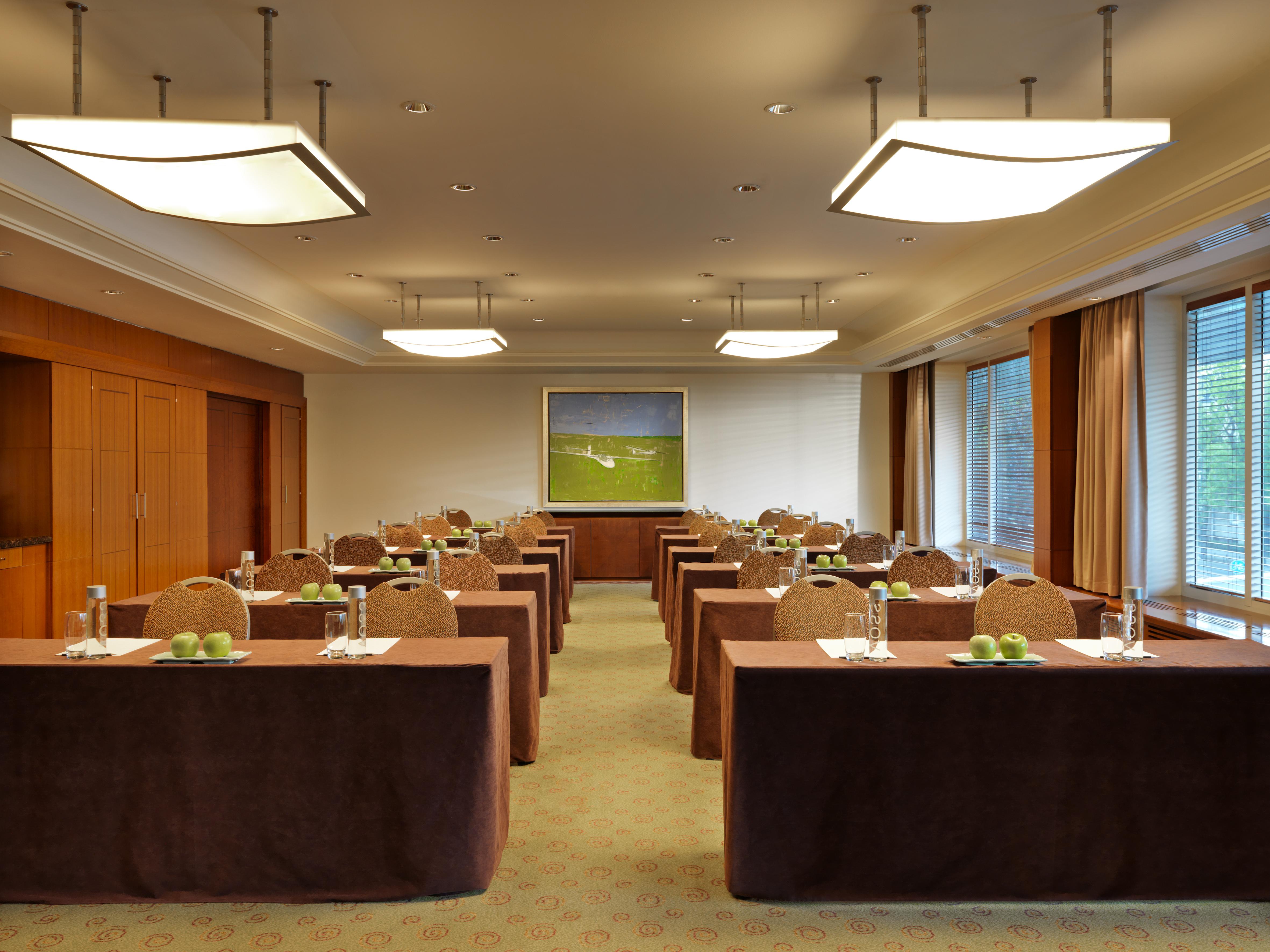 Regent Warsaw Hotel Buitenkant foto The photo depicts a conference or meeting room. The room is arranged with several rectangular tables set up in rows, each covered with brown tablecloths. On each table, there are glass water bottles and small green apples, suggesting preparation for 