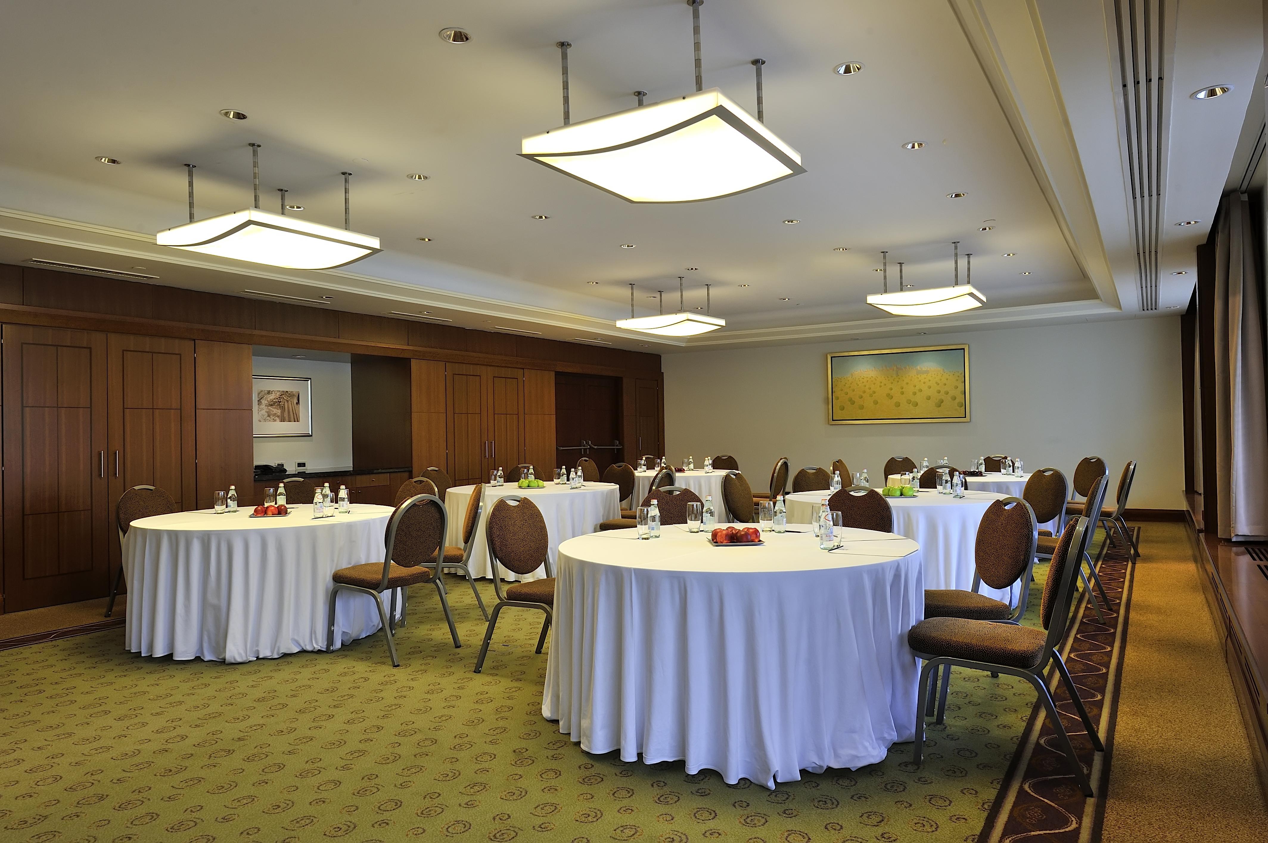Regent Warsaw Hotel Buitenkant foto The photo depicts a conference or meeting room. It features several round tables covered with white tablecloths. Each table has chairs around it, and there are items such as water bottles and possibly snacks on the tables. The room has modern lightin