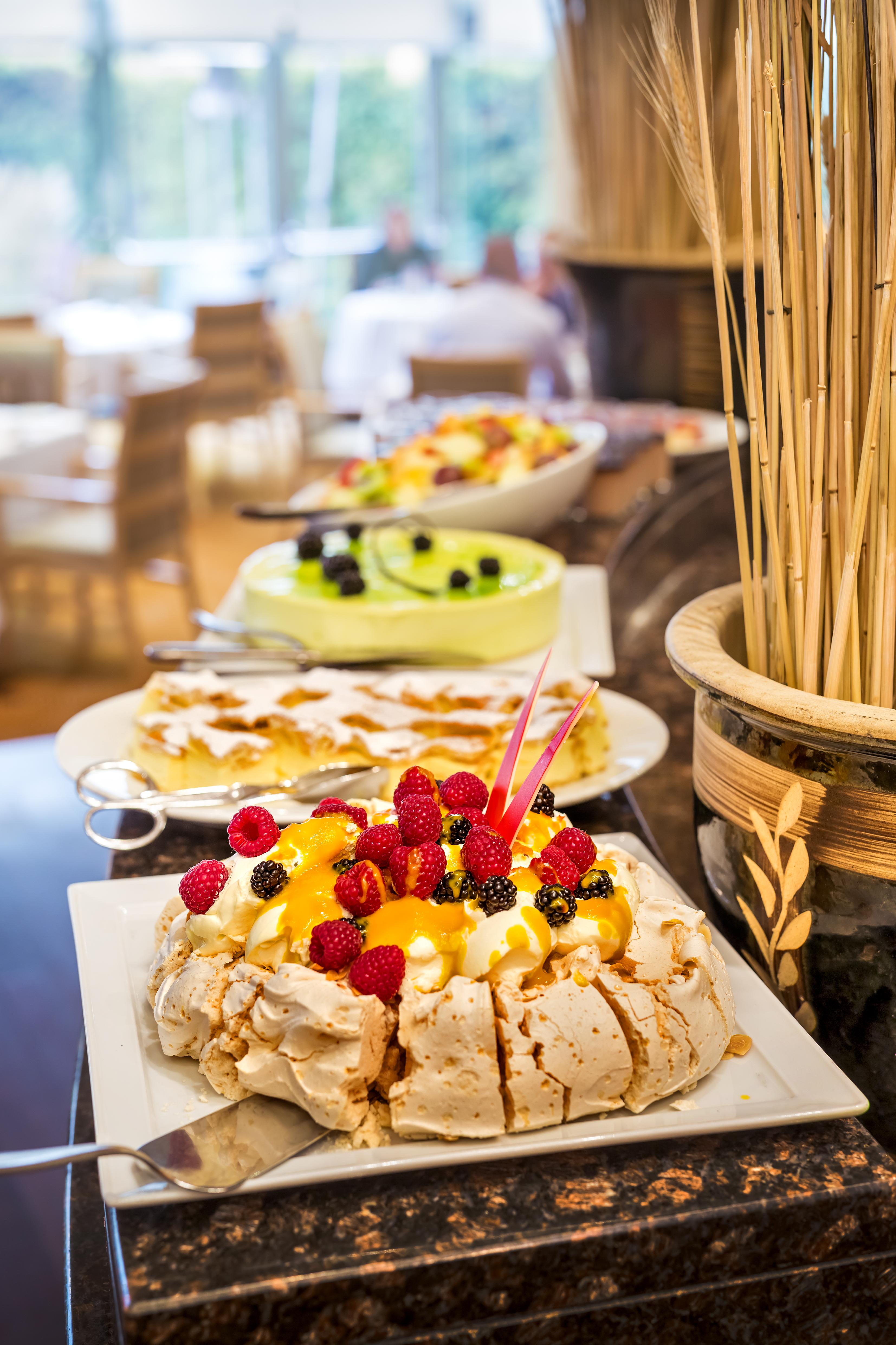 Regent Warsaw Hotel Buitenkant foto The photo shows a buffet display of various desserts. In the foreground, there is a large dessert topped with an assortment of colorful fruits, including raspberries, blackberries, and orange slices. This dessert is likely a type of meringue or pavlo