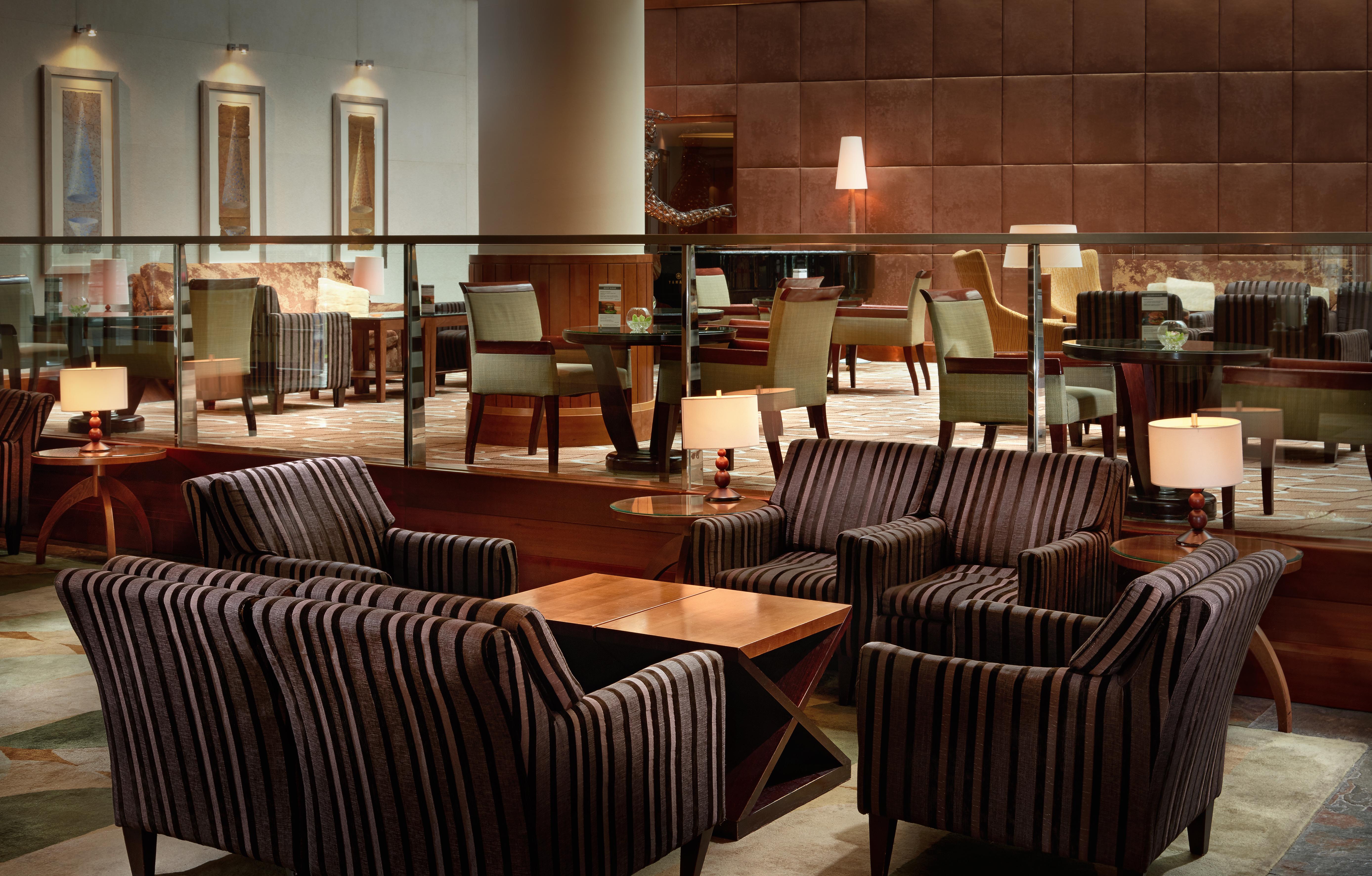 Regent Warsaw Hotel Buitenkant foto The photo shows a stylish and modern lounge area. There are several groups of upholstered chairs and couches, featuring a striped design. A wooden coffee table is placed in the center of the seating arrangement. The interior decor is sophisticated, w