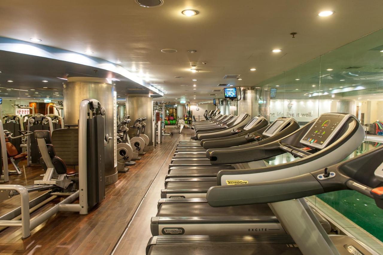 Regent Warsaw Hotel Buitenkant foto The photo shows the interior of a gym or fitness center. It features a row of treadmills lined up against one wall, with various other exercise machines and equipment visible in the background. The space is well-lit with artificial lighting, and ther